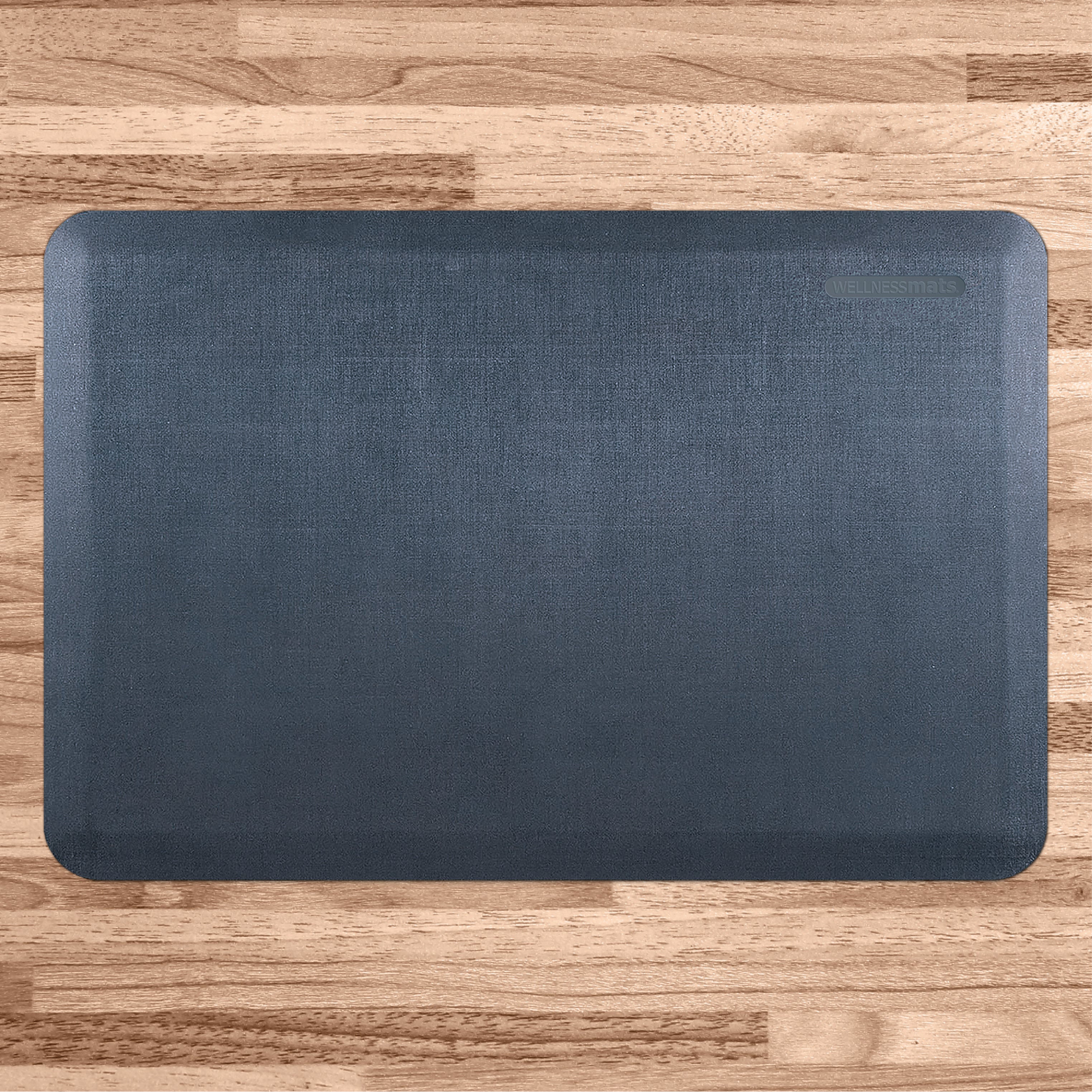 A 3'x2' Linen Lagoon WellnessMat on a light wood floor.