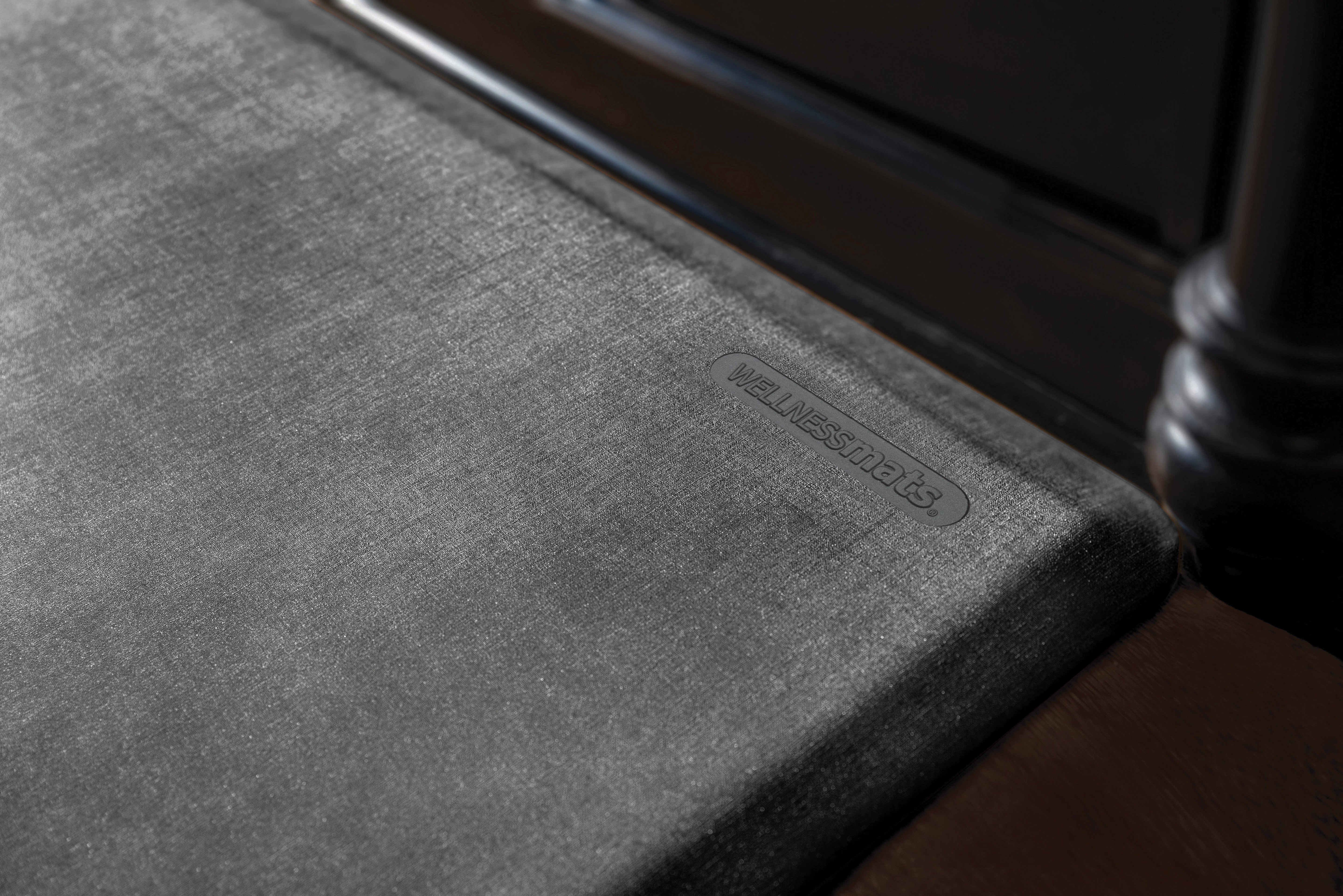 An up-close shot of a Linen Onyx WellnessMat in front a of a dark brown vanity.