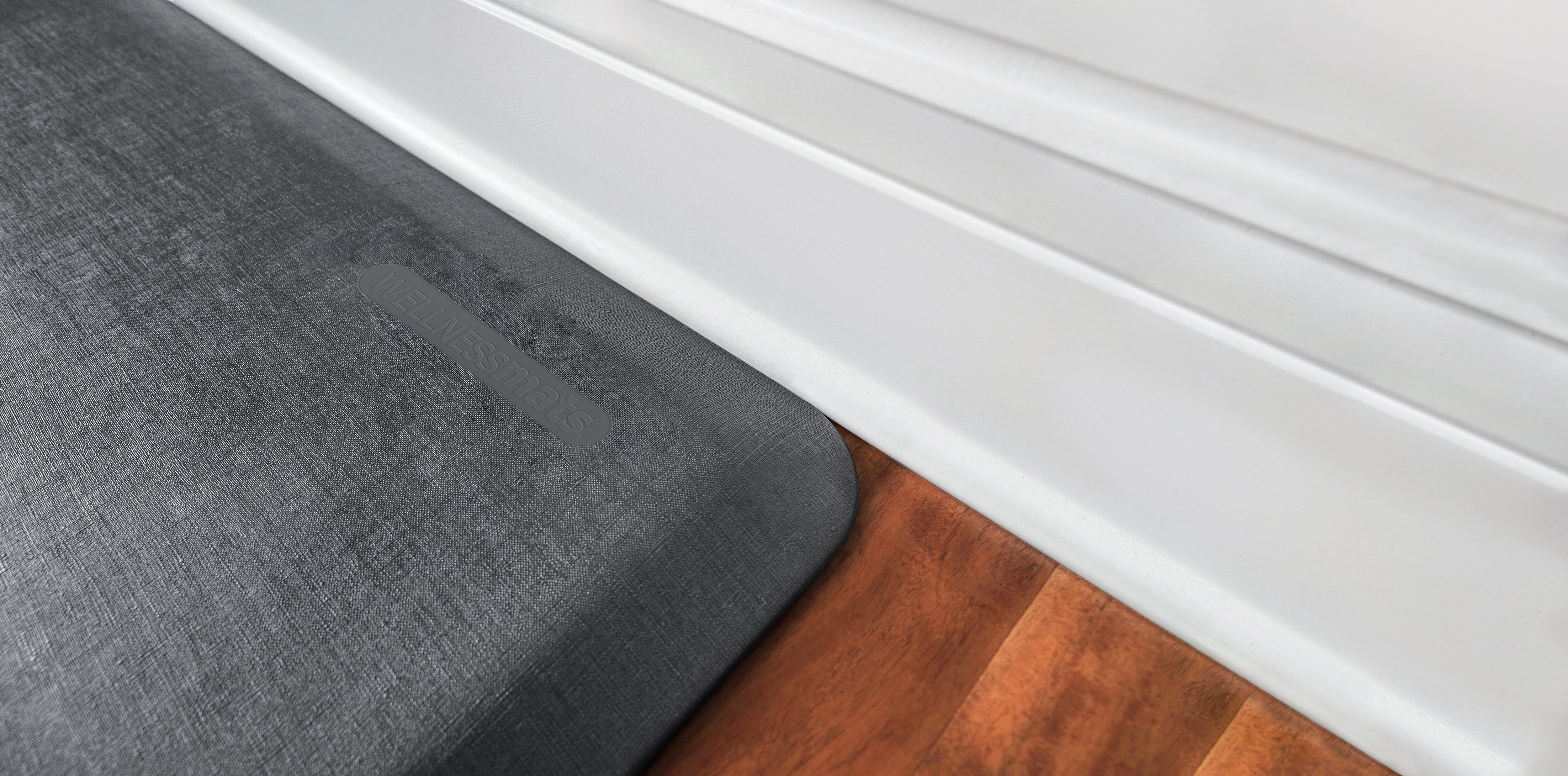 A up close shot of a 3'x2' Linen Slate WellnessMat on a wood floor.