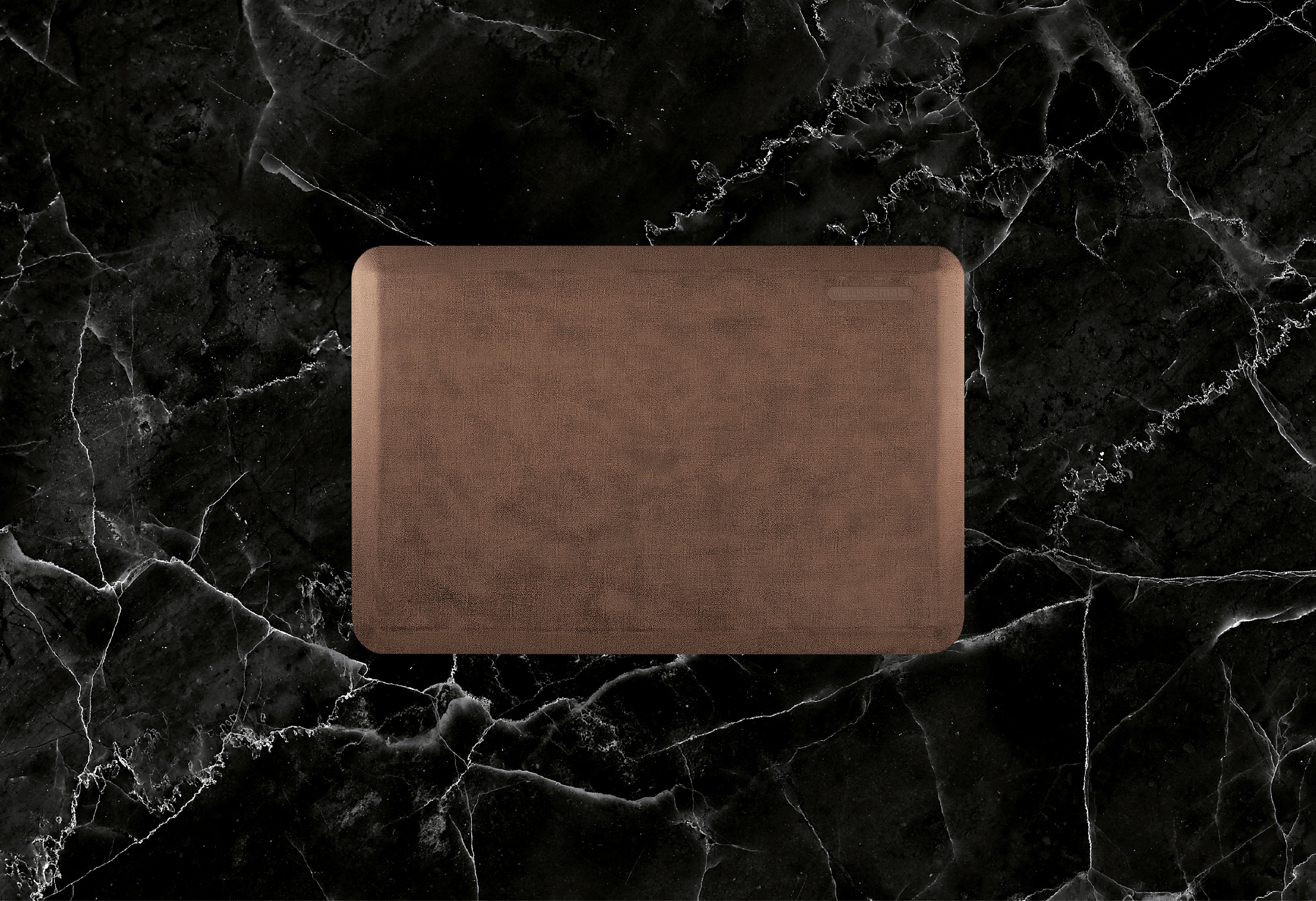 A 3'x2' Antique Light WellnessMat on a black marble floor.