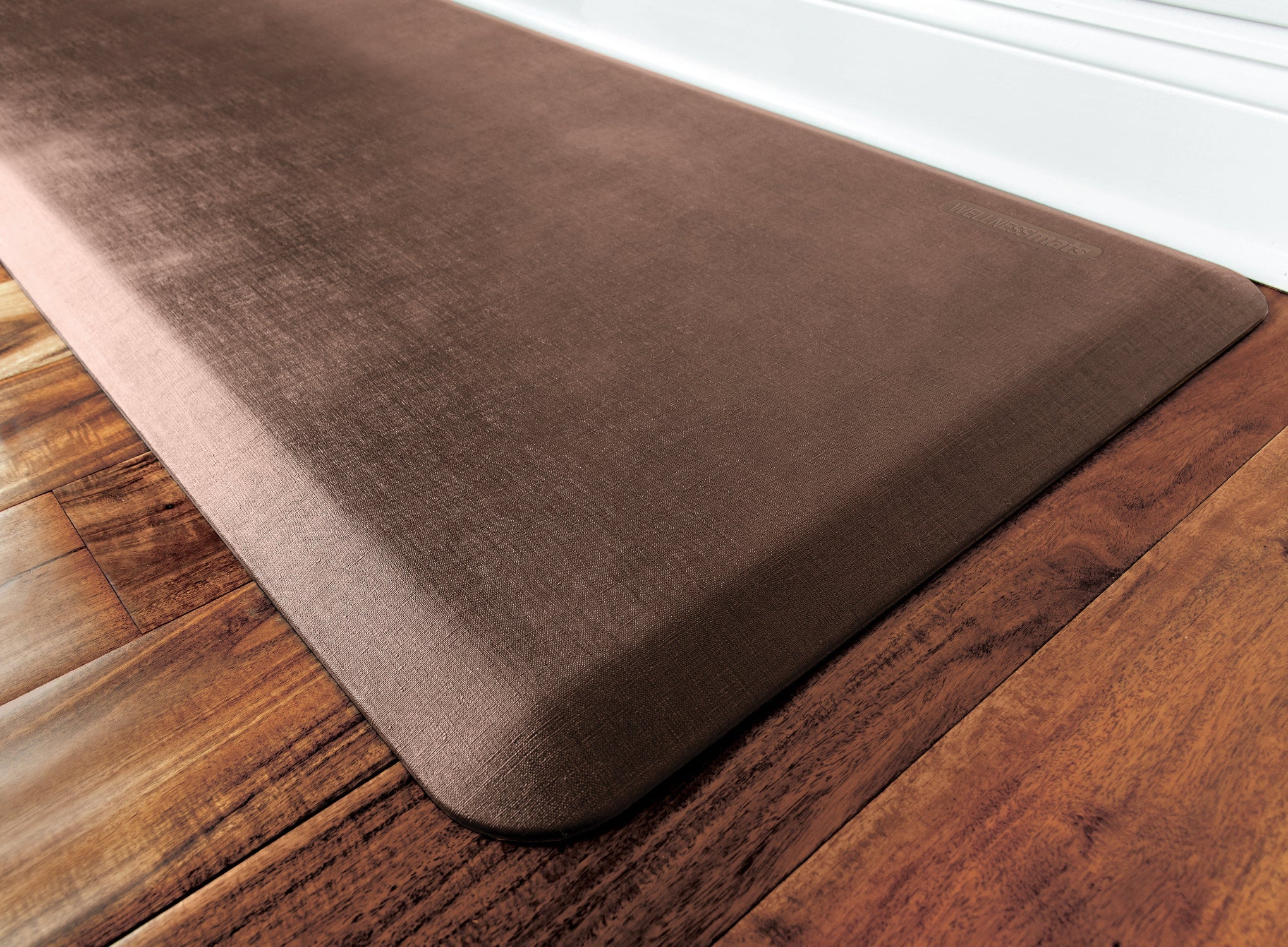 An up-close shot of 6'x2' Antique Light WellnessMat on a wood floor.